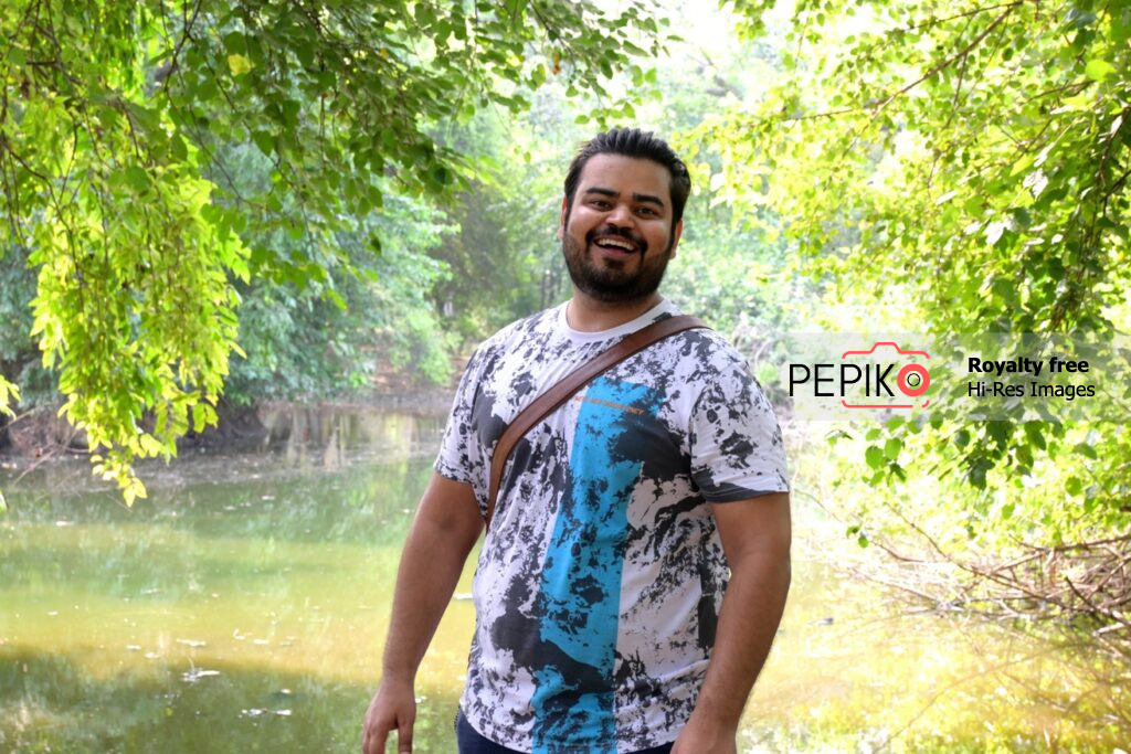 
									Charming man posing in forest with water pond in background