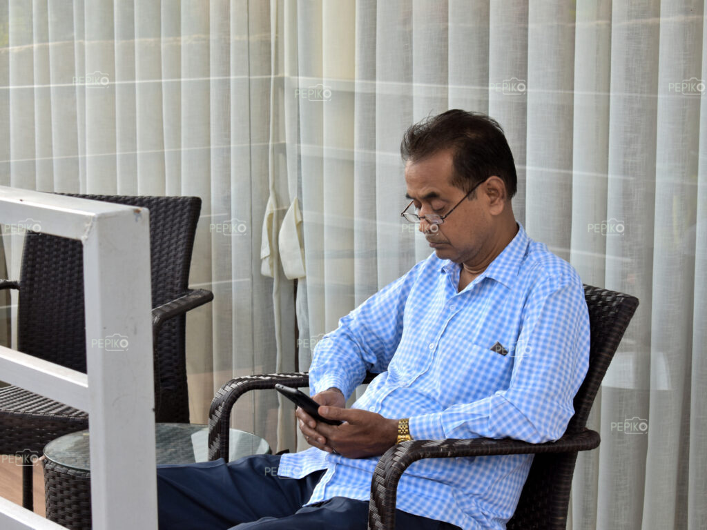 Picture of old / mature person using cell / mobile phone at outdoors