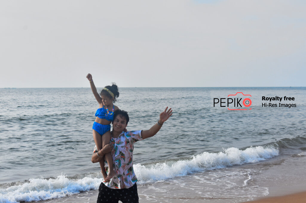 Young child and man travelers in GOA India enjoying at water sand beach