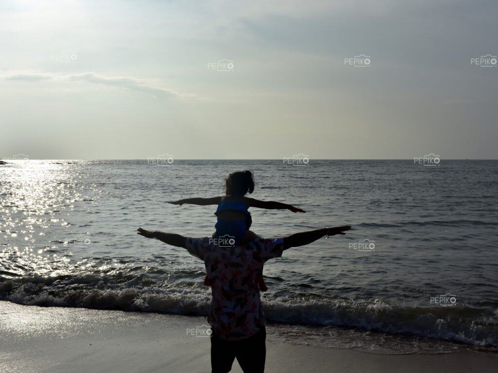 Another picture of Young child and man travelers in GOA India enjoying at water sand beach