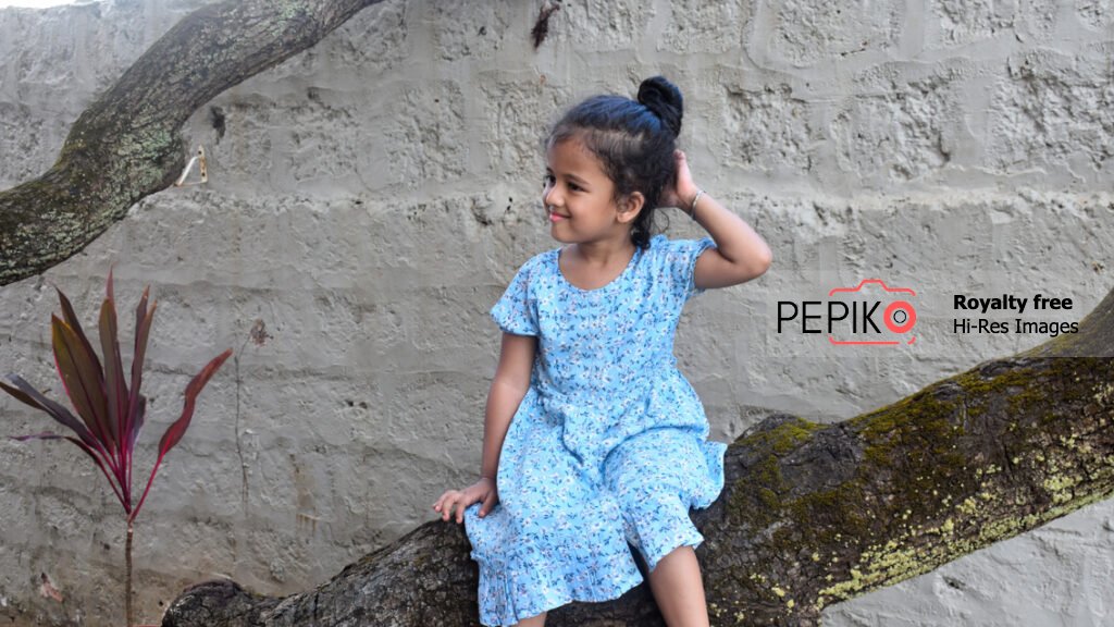 
									Young kid at posing while sitting on tree