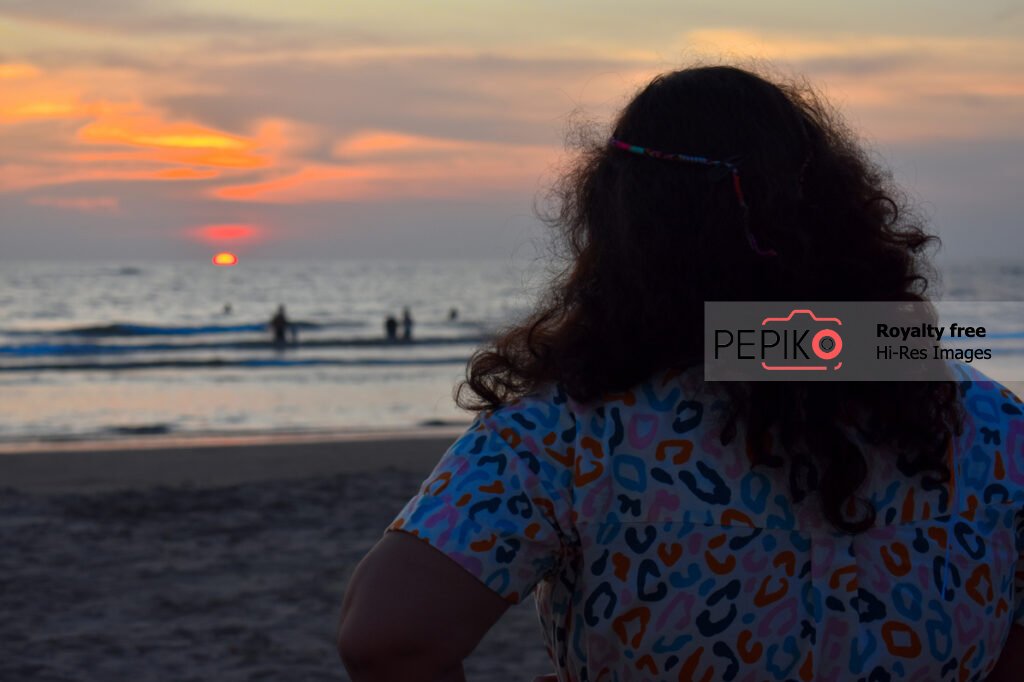 
									Beautiful orange view of sunset on beach with women looking towards the Sun