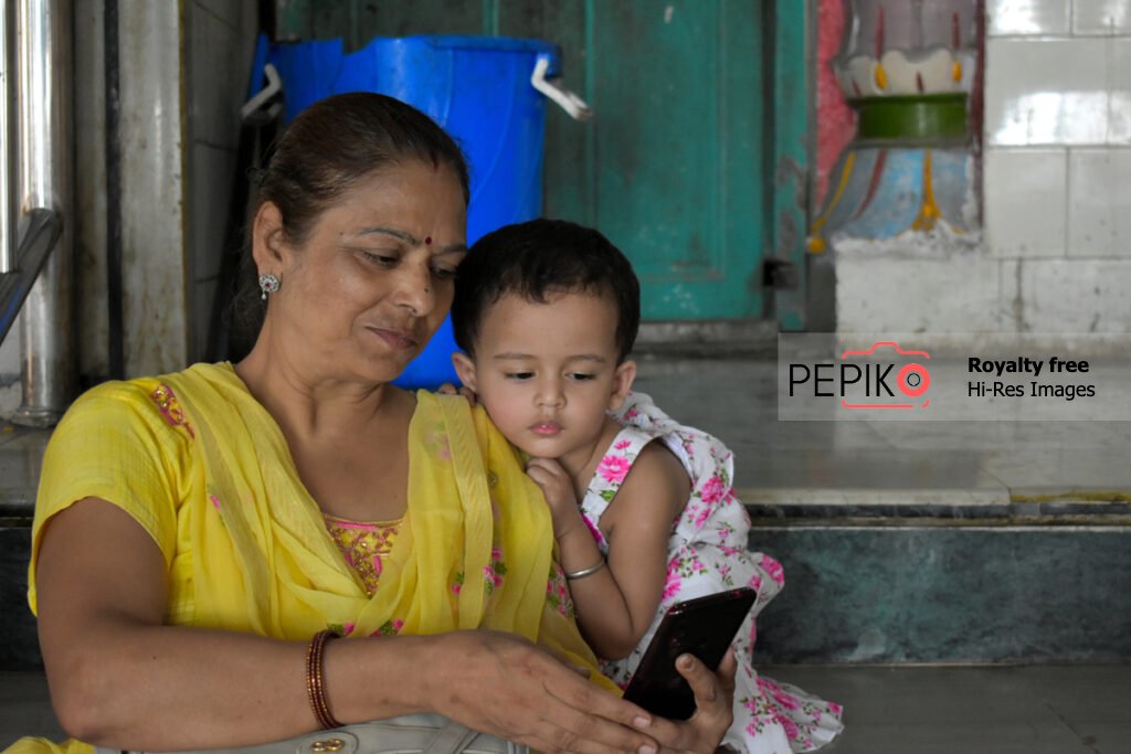 Picture of mature women and a kid showing their interest / addiction in cell / smart phone