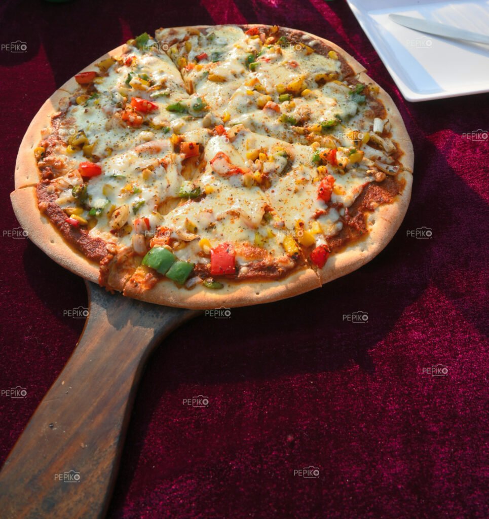 Closeup of thin crust vegetable pizza loaded with cheese