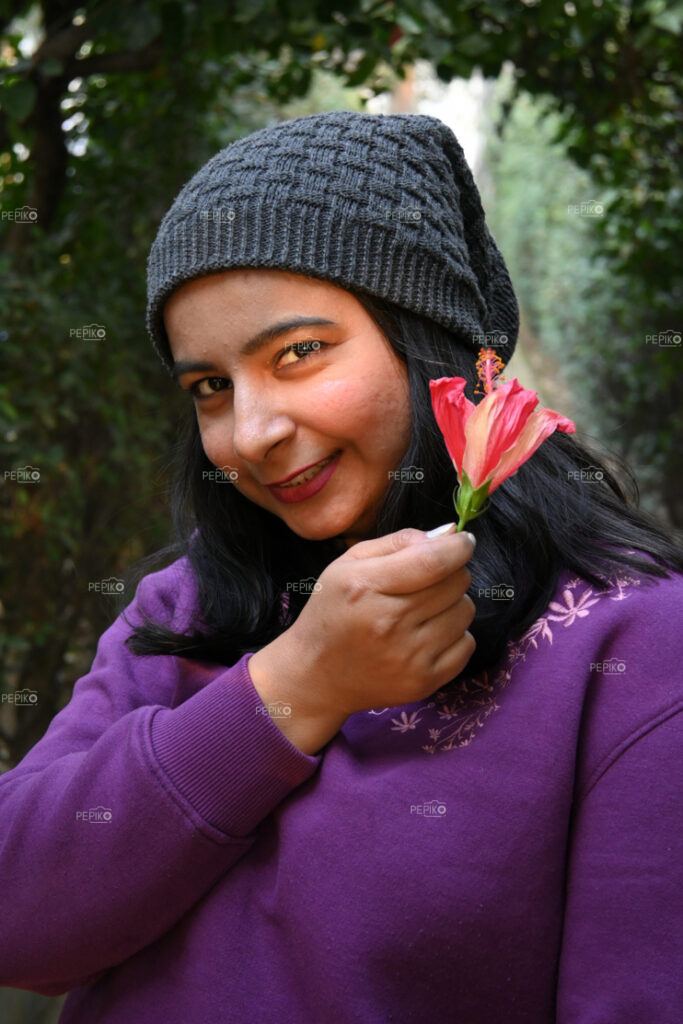 Indian girl in purple top posing with red flower