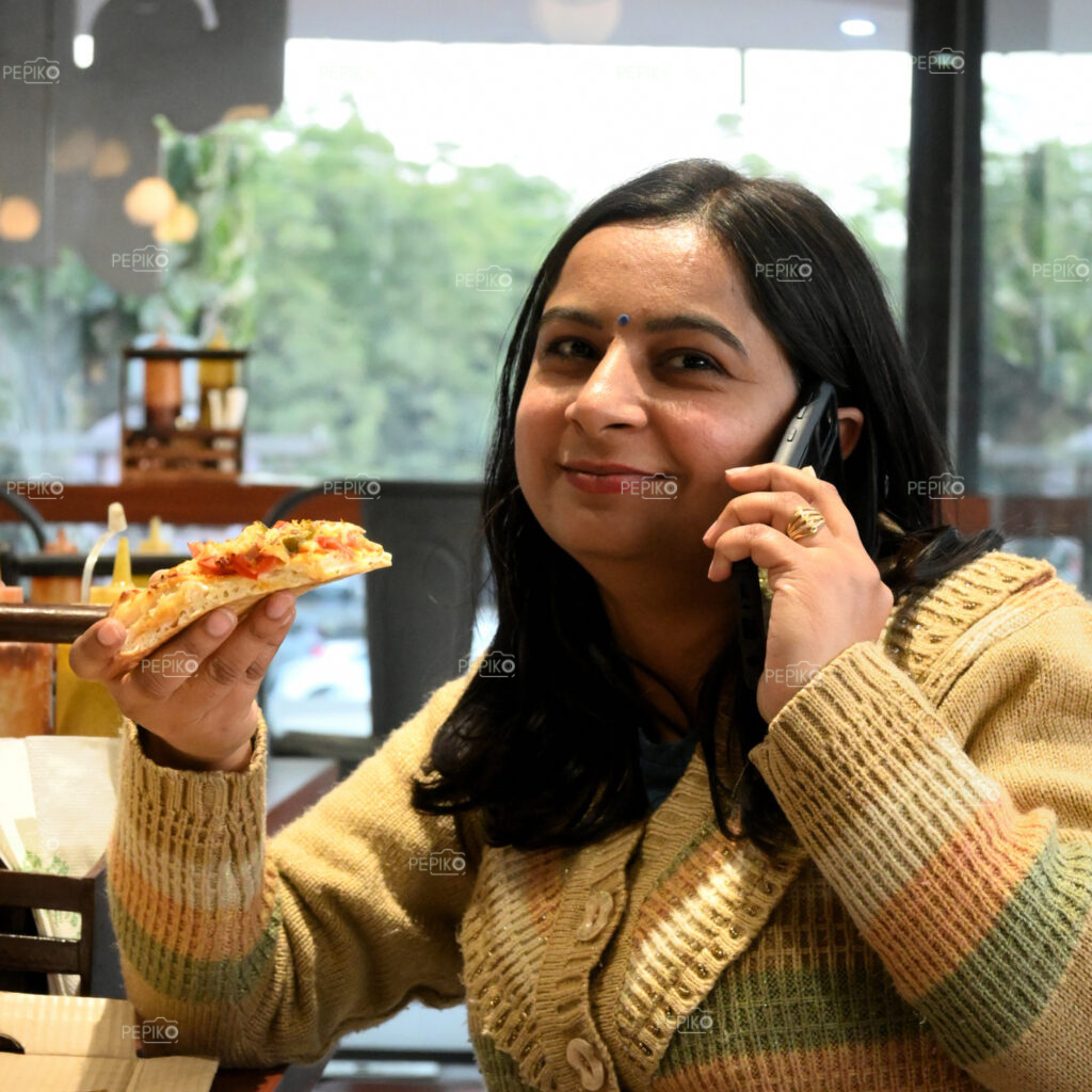 Smiling women talking on phone and having her pizza